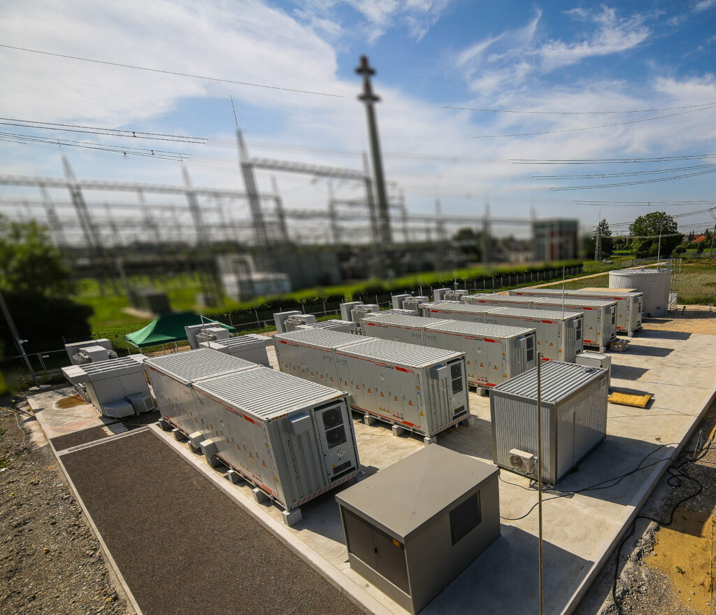 ju:niz Batteriespeicher SMAREG 12 mit Batteriespeichercontainern und Hochspannungsnetz im Hintergrund